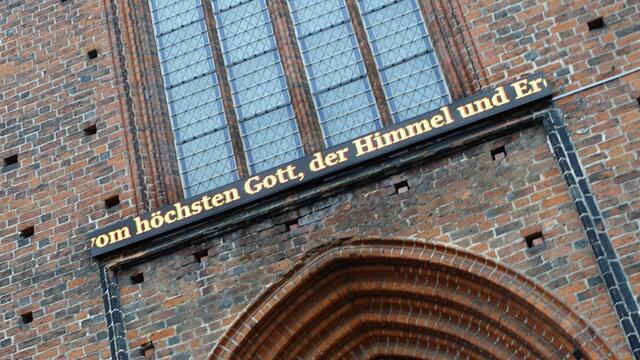 Über dem Eingangsportal des Domes zum Markt hin läuft der Bibeltext auf einem leuchtend gelben LED-Band in einer Endlosschleife. Foto: Helmut Kuzina