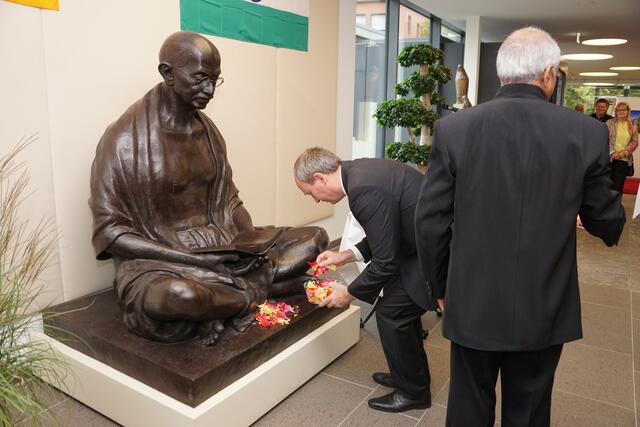 Der Rathauschef mit Blumen an der Gandhi-Statue im Rathaus