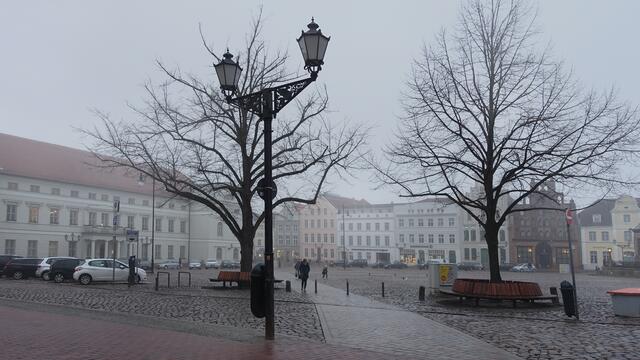 Es ist einer der Tage, an denen es ganz unspektakulär allmählich heller wird. Auf dem Marktplatz geben die (nachgepflanzten) so genannten "Gerichtslinden" und die Straßenlaterne der flauen Stadtansicht Konturen. Foto: Helmut Kuzina