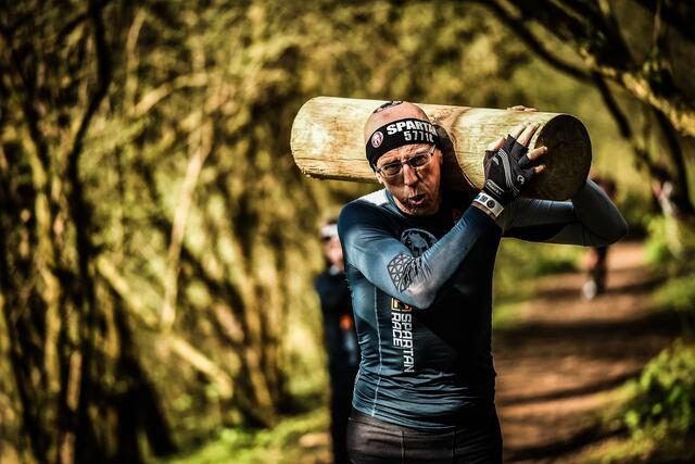 Schweren Holzstamm durch einen Parcours tragen