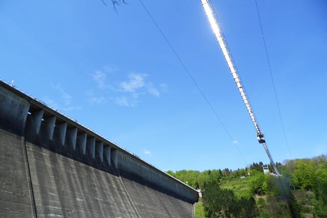 Parallel zur Sperrmauer überspannt die Hängebrücke das weite Tal.