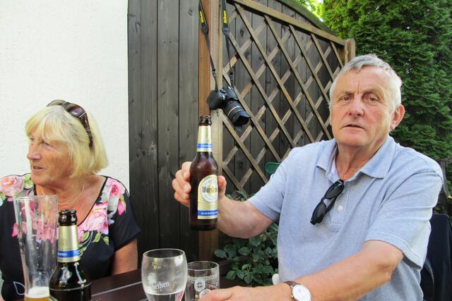 Hier scheint es nur so, als ob Volker Beilborn die Nikon-Kamera an den Nagel gehängt hätte. Die Schnappschusswaffe hängt an einer Rankhilfe während ihr Eigentümer ein alkoholfreies Erfrischungsgetränk zeigt. Links Christine Eich im Gespräch.