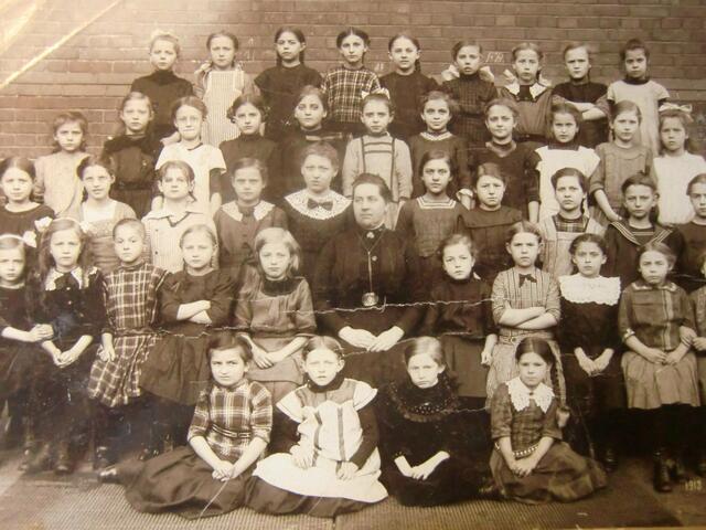 Meine Mutter Martha Hagemann, später Wettig, sie steht über der Lehrerin, hat eine weiße Schleife im Haar. Das Foto ist ca. 1910 entstanden in Hannover-Nord.