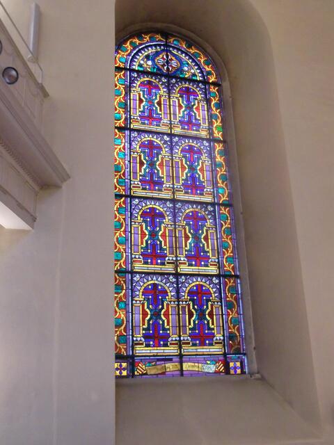 Auf beiden Seiten des Altars sind vier Fenster mit bunten Scheiben