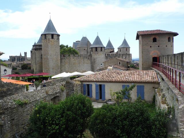 Im Inneren der Anlage ist so mancher Hinterhof mit Garten versteckt. Im Hintergrund die Burg mit ihren neun Türmen.