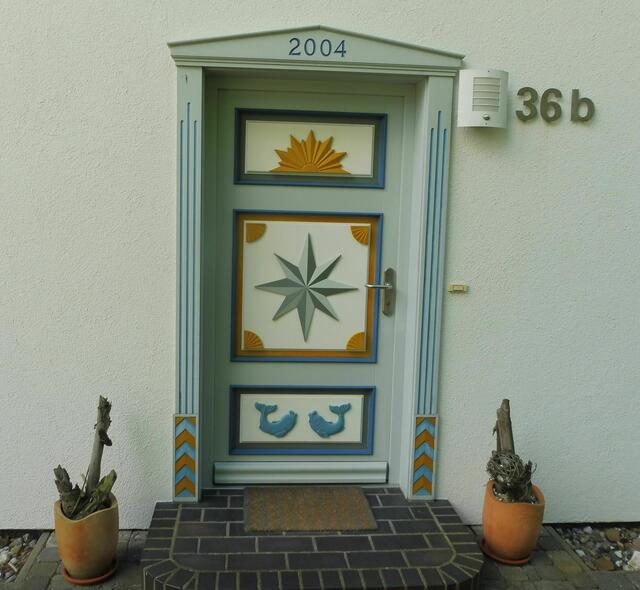 Südstraße 36b. Ornamente = Oben: aufgehende Sonne, Mitte: Stern mit 8 Spitzen, erinnert an eine Kompassrose, unten: Delfine, hat nur einen dekorativen Charakter.