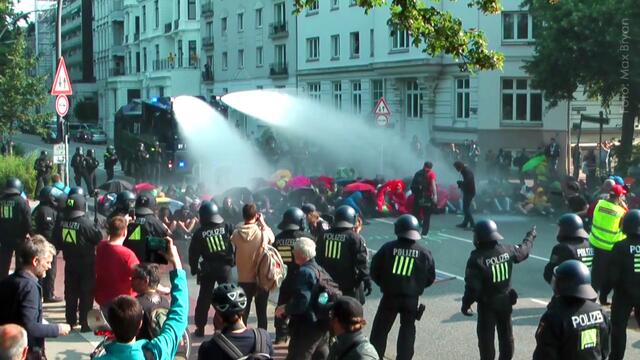 Aufnahme vom Morgen des 7. Juli 2017. Trotz massiven Beschusses durch den Wasserwerfer blieben die Reihen der Sitzblockierer geschlossen. Ein herausragendes Beispiel friedlichen Protest´s - wie er auch ganz ohne Steine effektiv und zielführend sein kann. Trump musste daraufhin die Route ändern. Die Aktivisten saßen nämlich auf einer sogenannten "Protokoll-Stecke" :-) (Foto: Max Bryan) https://www.facebook.com/notes/max-bryan/tapferes-schneiderlein/1985111944840044/