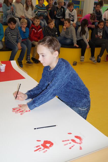 Eliah macht seinen rote Hand Abdruck und unterschreibt mit seinem Namen