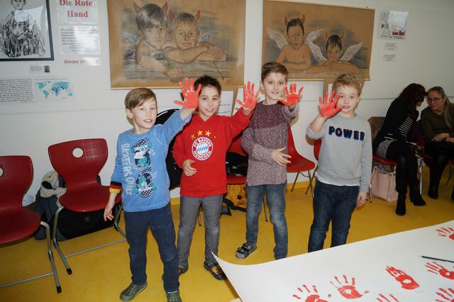 Simon, Max, Noel und Pauli vor ihren Porträts mit roter Hand