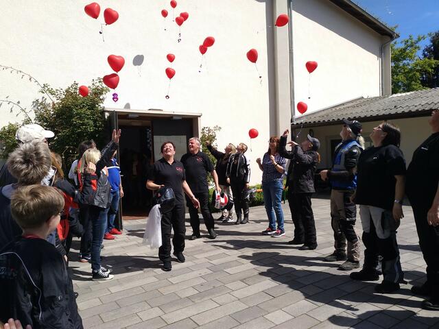Bikerfreunde aus beiden Vereinen liessen rote Herzen in den blauen Himmelsteigen, als das Biker-Brautpaar die Kirche verließ | Foto: Martin Pitz / Motorradfreunde Marburger Land