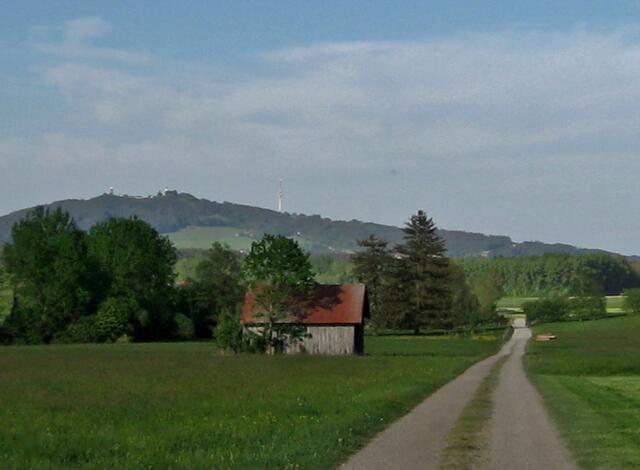 Die Schiebestelle bei der frisch gemähten Wiese habe ich hinter mir. Nun geht es mit einem schönen Blick auf den Hohen Peißenberg, auf schottrigem Weg, weiter.
