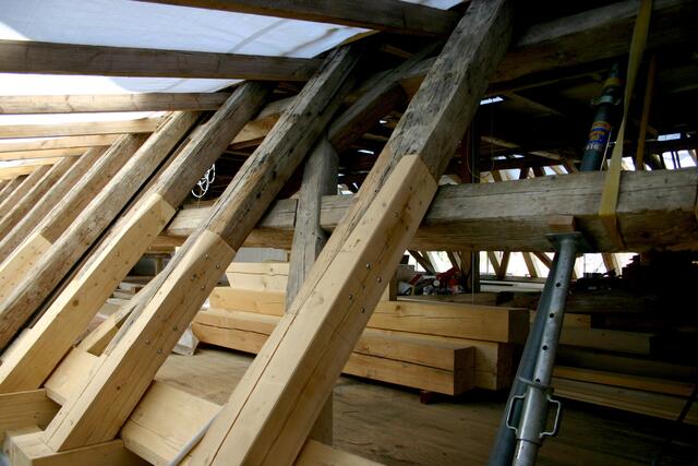 Mit Stützen und Spanngurten werden die Stuhlbalken gesichert, während an die Sparren neue Enden angeschäftet werden.