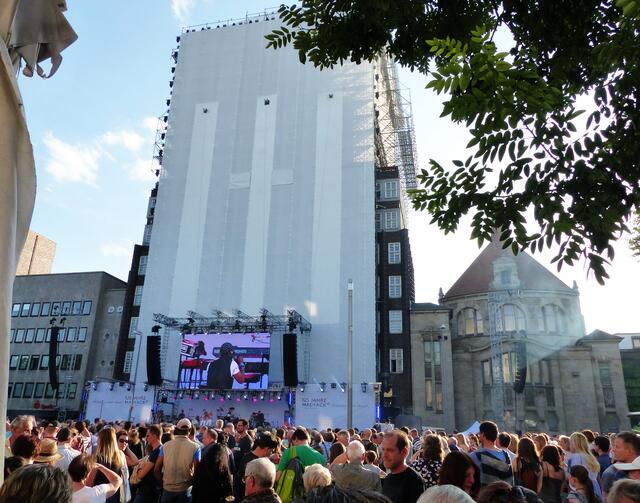 Da die Kuppel des Anzeiger-Hochhauses zurzeit saniert wird, steht vor der Fassade ein Baugerüst. Doch das stört an diesem Tag nicht. Im Gegenteil, wird doch die weiße Fläche später zur Riesenleinwand.