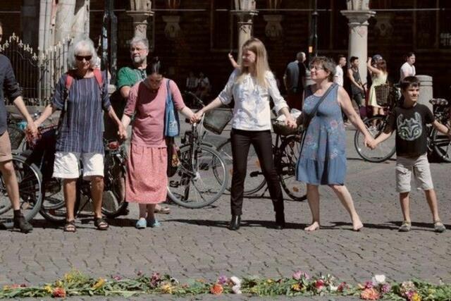 Zum Abschluss der Mahnwache bildeten etliche Teilnehmerinnen und Teilnehmer um das Peace-Zeichen aus Blumen herum einen Menschenkreis, um einen Ulmentanz durchzuführen. Dritte von rechts: Doris Achelwilm, Bremer Bundestagsabgeordnete (Die Linke). | Foto: Bundesverband Arbeiterfotografie, Georg-Maria Vormschlag