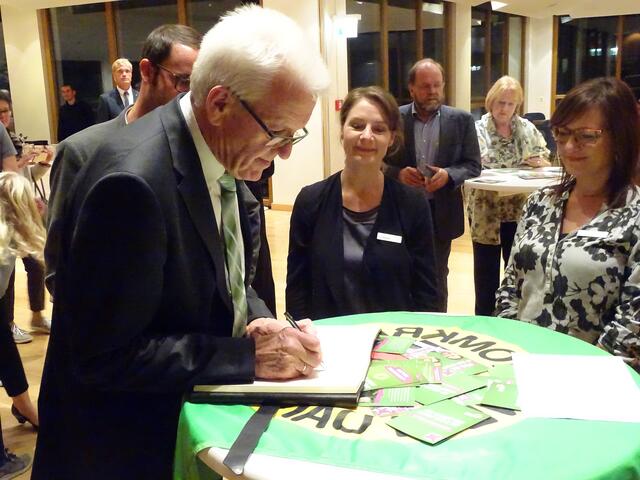 Der Ministerpräsident trägt sich ins Gästebuch des Forums ein.