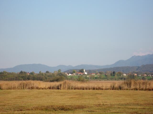 Blitzblanke Dörfer und ein Kirchturm. Weit dahinter, ein Teilausschnitt vom Wettersteingebirge. Wer nicht genau weiß, wo das sein könnte, denke sich die Gegend um den Kochelsee/Walchensee.
