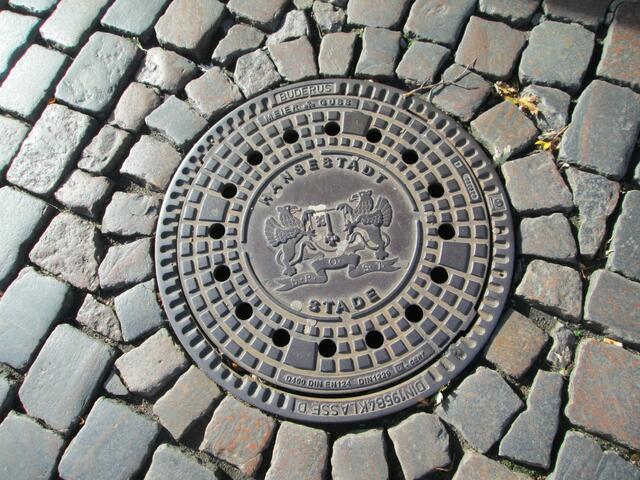 Kanaldeckel der Hansestadt Stade. Das Wappen mit dem  Spruchband „S. P. Q. ST.“, hier mit einem Punkt zuviel. (Senatus Populusque Stadensis, also in deutscher Sprache: Der Rat und die Bürger von Stade).