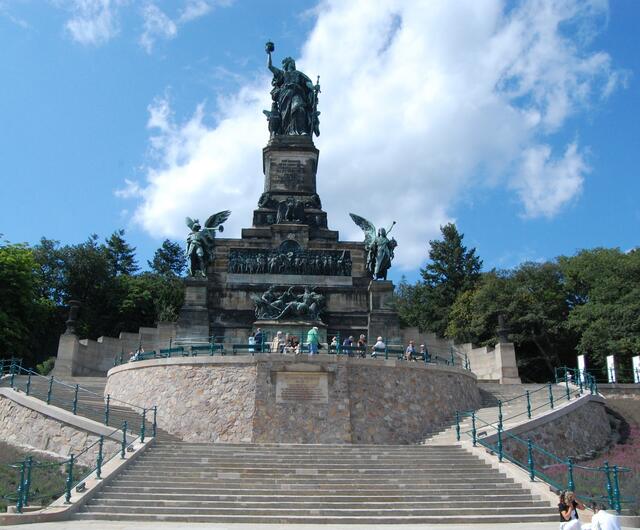 Vor uns baut sich das monumentale Denkmal auf. Die Germania blickt, in der rechten Hand die Reichskrone hochhaltend, links auf das Schwert gestützt, in die Ferne.