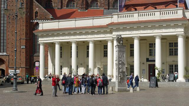 Immer wieder ziehen Touristengruppen über den Marktplatz, um sich das Löwendenkmal vor dem Säulengebäude erläutern zu lassen. Foto: Helmut Kuzina