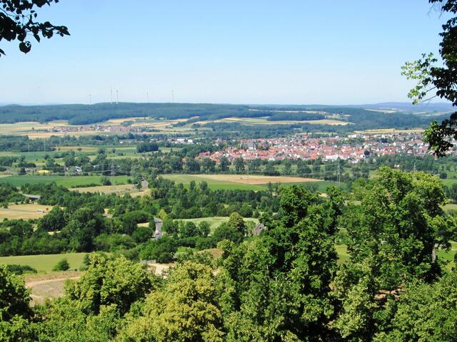 Hier sind in der Bildmitte Kirchhain, links der Ort Stausebach vor den Windrädern und rechts zwischen den Wäldern hinter Kirchhain der Ort Himmelsberg zu sehen.