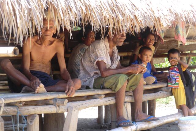 Unter dem dichten hohen Grasdach kommt man zusammen. Die brutale Hitze im Sommer vertreibt ein stetes Lüftchen, das durch die Wände aus Holzbrettern und Bambus und Matten aus Palmblätter hindurchziehen kann. Unter der erhöhten Plattform für die Menschen leben die  Haustiere: Schweine, Hühner, Ziegen und Hunde. Nur  beim Begräbnis eines Verwandten dienen all diese vier Fleischsorten, eben auch Hunde zur Verköstigung.