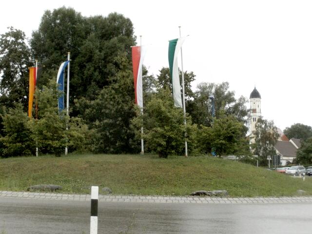 Der Kreisverkehr am östlichen Ortseingang mit der Pfarrkirche St. Martin im Hintergrund. Nicht nur die Fahnen wurden naß, sondern auch deren Monteure.