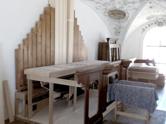 Die großen historischen Holzpfeifen des Subbass-Registers sind bereits montiert. Rechts daneben lagern die Teile des historischen Prospekts, von denen einige an der Frontseite bereits verbaut wurden.