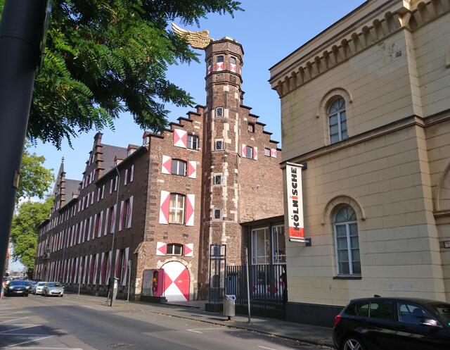 Das Zeughaus am Tag. Am Turm fällt ein goldener Flügel auf.