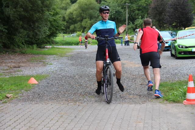 Martin Vogel kommt ohne Schuhe auf dem E-Bike eines Streckenpostens ins Ziel.
