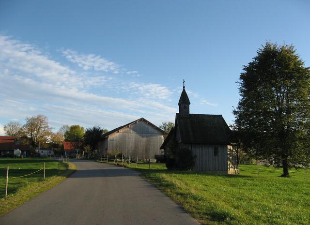 Rückblick zur Kapelle. Darüber immer noch der blaue  Himmel mit seinem streifenartigen Wolken-Teppich. Gleich bin ich wieder im Ortsteil Echelsbach angelangt  und habe somit die Radtour ins Moor (altbairisch: Filz), als geschlossenen Kreis, vollendet.