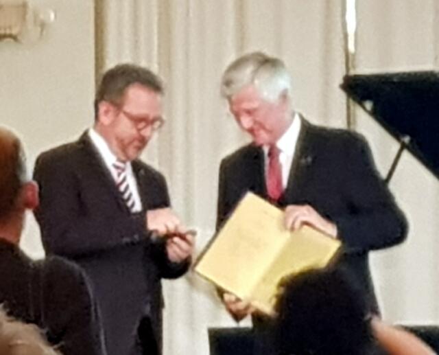 Dr. Bernd Fabritius  händigt dem überraschten Christian Knauer Urkunde und Abzeichen aus