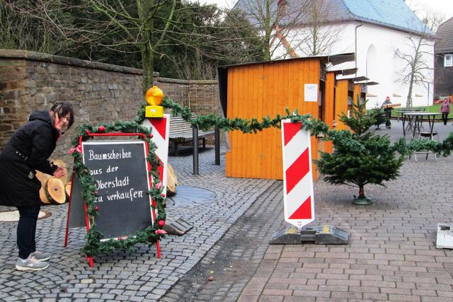 Nicole Bienhaus schmückt das Hinweisschild zum Verkauf von Baumscheiben aus der Oberstadt, die nach dem Fällen von Bäumen auf dem Kinderspielpatz am Marktplatz geschnitten wurden.