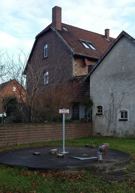 Unter dem Betondeckel verbirgt sich der Spring, die ehemalige offene Siedlungsquelle. Wenn man so will, der Ursprung des menschlichen Lebens in Groß Lafferde. Dahinter liegt das Grundstück des ehemaligen Oberen Gemeindebackhauses