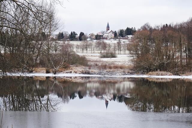 der Kirchturm der Bonhoeffer  Kirche von Friedrichsbrunn spiegelt sich im Gondelteich