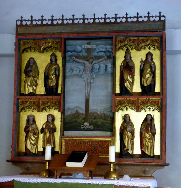 Acht geschnitzte Heiligenfiguren umgeben das Kruzifix. 1899 hatte man festgestellt, das die Flügel des Altars fehlen, die nie mehr gefunden wurden.