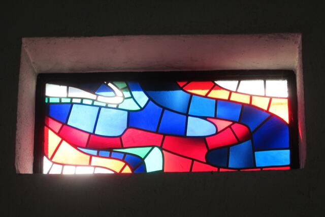 Lichtdurchlass mit Mosaikband aus vorwiegend blauen und roten Teilen.