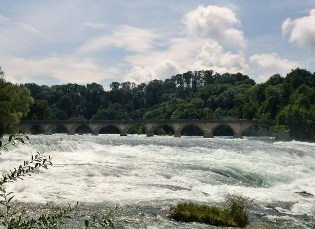 Blick auf die Brücke und das Rheinwasser, bevor es am Felsgestein 23 m hinab stürzt.