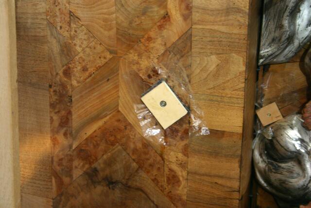 Kleber einspritzen, mit Folie abdecken und mit Sperrholzbrettchen und Schraube pressen: Das lose Furnier wird beinahe quadratzentimeterweise wieder befestigt.