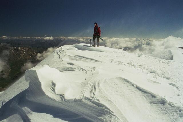An seinem höchsten Gipfel, dem Mittelgipfel. Eiskristalle flirren durch die Luft und ziehen nach Italien hinüber. Sie schleifen Facetten in den harten Firn.