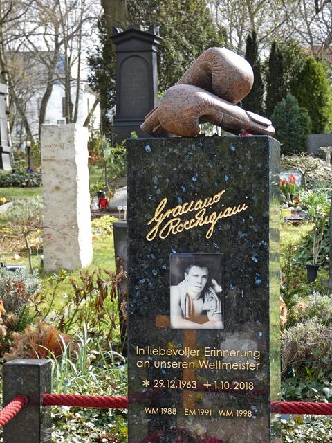Grabstein Graciano Rocchigiani († 2018 – Boxer) mit Boxhandschuhen auf dem Stein