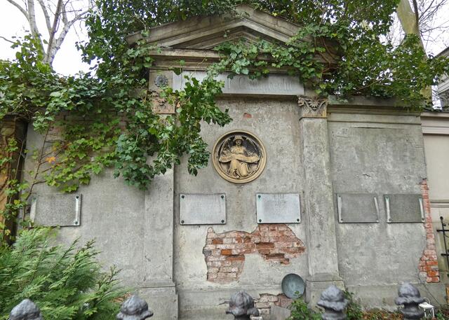 Älteres Wandgrab mit unleserlichen Tafeln, der Putz bröckelt bereits.