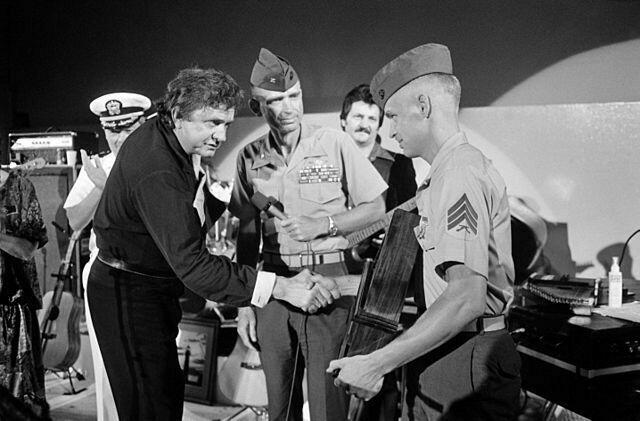1986 - Johnny Cash erhält während seines Auftritts eine Auszeichnung von einem Marine-Sergeant für Militärangehörige an der Marinestation. | Foto: PH1 GARY RICE, USN - ID:DN-SN-88-00642 / Service Dargestellt: Navy