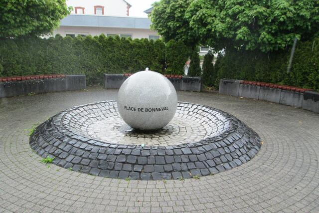 Der Brunnen auf dem Place de Bonneval in Allendorf (Eder). Auf dem vorderen Rand ruht der Wanderstein der FuldatalSteine.