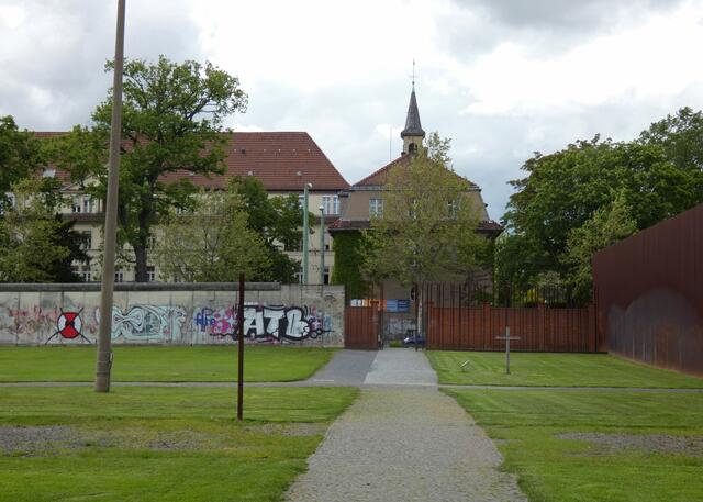 Blick vom Friedhof über den "Todesstreifen" zur Bernauer Strasse mit Mauerresten. Dieser Teil mit dem Kreuz gehörte auch zum Friedhof und wurde eimgeebnet.