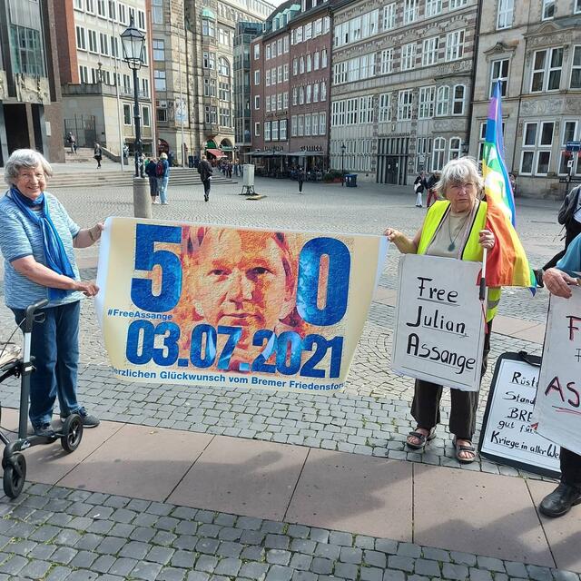 Helga Garde  (links) und Gisela Vormann gratulieren Julian Assange zu seinem 50. Geburtstag.