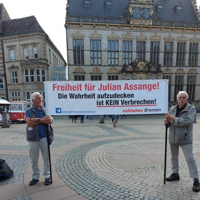 Dieter Götzel (links) und Anton Willens gratulieren Julian Assange zu seinem 50. Geburtstag.