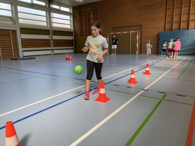 Den Ball an den Hütchen vorbeiprellen.