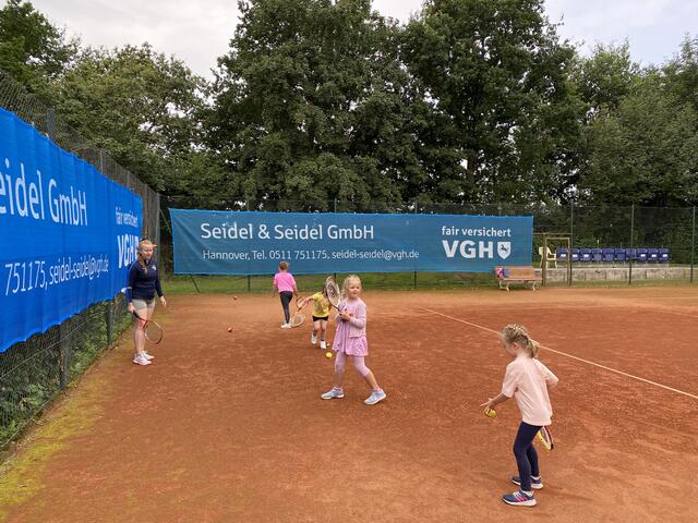 Larissa zeigt den kleineren Mädchen spielerisch mit Ball und Schläger umzugehen.