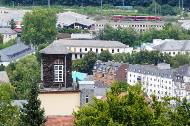 Im Vordergrund steht die Gerling-Sternwarte des Fachbereichs Physik. Christian Ludwig Gerling errichtete sie 1841 im Turm des Gebäudes Renthof 6. Bekanntester Nachfolger als Direktor der Sternwarte war Alfred Wegener. Der Meteorologe, Astronom, Geophysiker und Grönlandforscher arbeitete in Marburg von 1909 bis 1919. Oben rechts ist ein roter Verbrennungstriebwagen der Baureihe 642 (VT 642) der Kurhessenbahn auf den Gleisen zu erkennen.