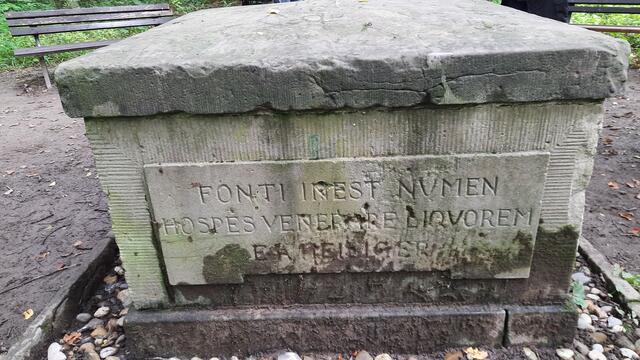Denkmal am Heiliger Brunnen / an der Heiliger Quelle. ... 1953 wurde an der vierten Seite der Steineinfassung eine Inschrift in deutscher Sprache ergänzt, die die drei lateinischen Sprüche übersetzt zusammenfasst: 
„Komm / Siehe / Trinke / Gottheit wohnt inne dem Born / O Gast verehre die Quelle / Trinkend schöpfte daraus die Flüssigkeit Heiliger einstmals 1794."  ... Eine Radtour des https://www.ADFC-Langenhagen.de